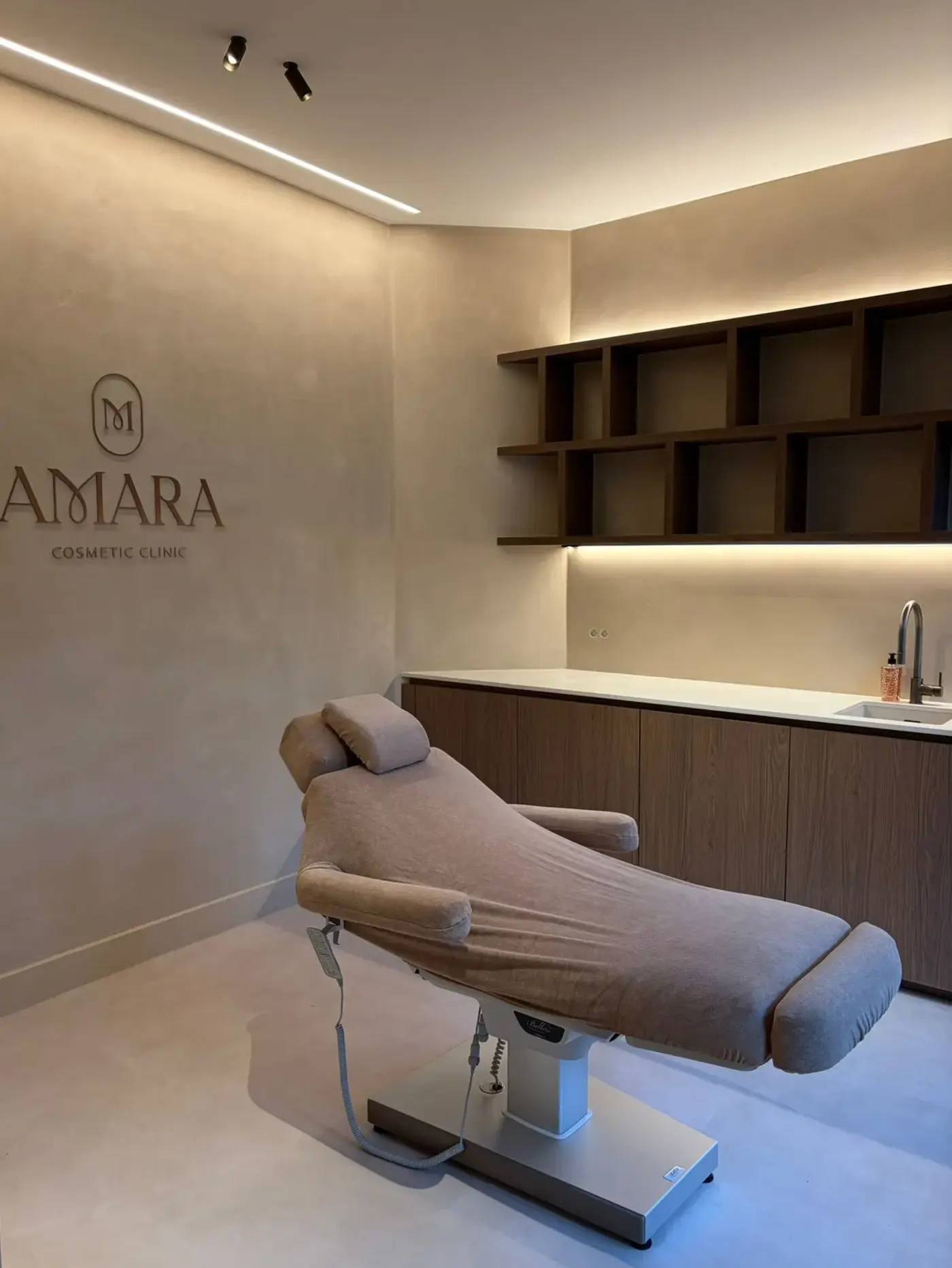 Behandelkamer van Amara Cosmetic Clinic met het logo op de muur